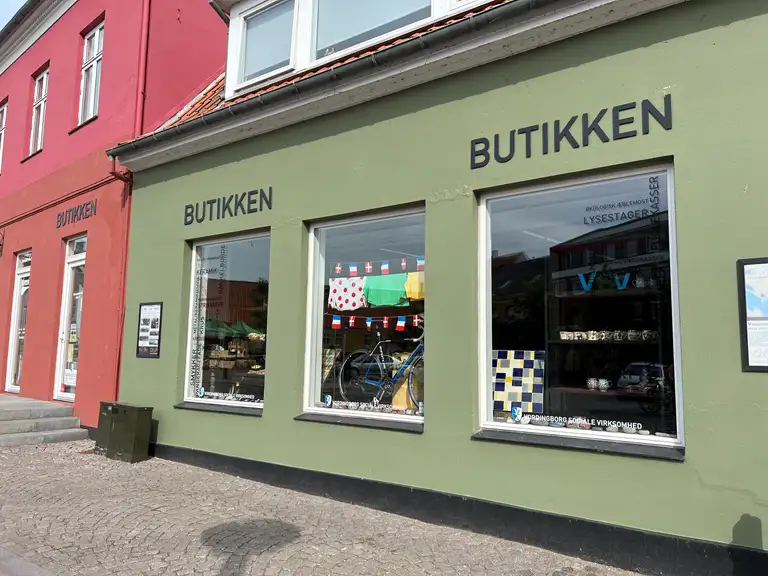En butiksfacade ud imod en bygade. Den hedder "Butikken", og er en del af "Vordingborg Sociale Virksomhed".